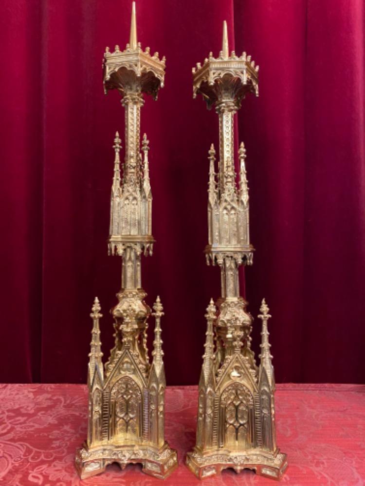 A pair of gold-plated and bronze church candle holders. …